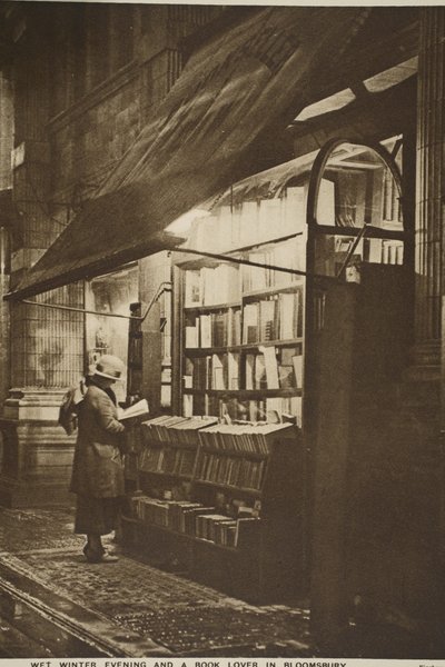Examining a book outside a second hand bookshop on a wet winter evening, Bloomsbury by English Photographer